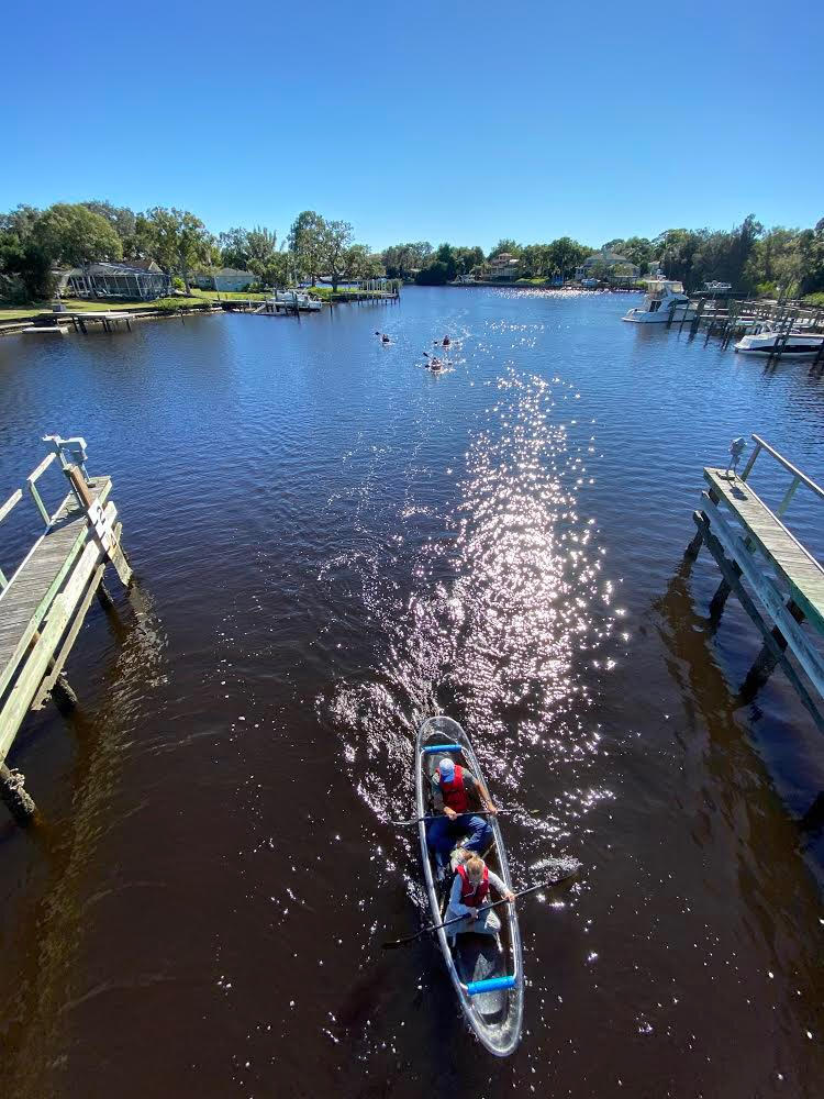 a boat floating along a river next to a body of water
