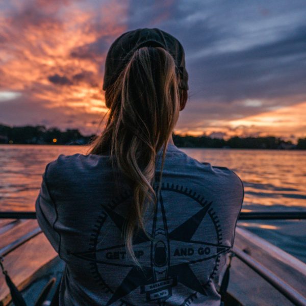 a woman sitting next to a body of water