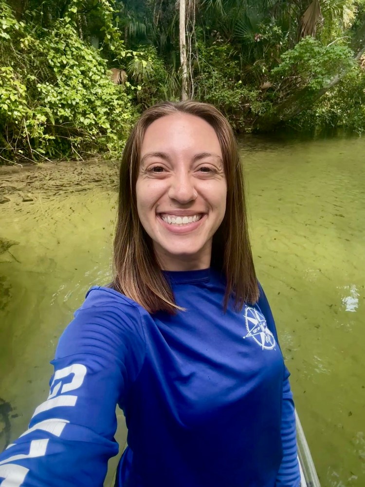 a person smiling next to a body of water