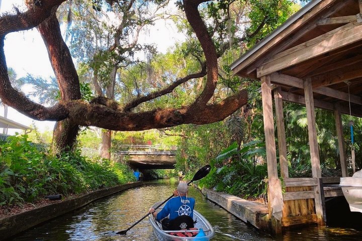 a man riding on the back of a boat next to a river