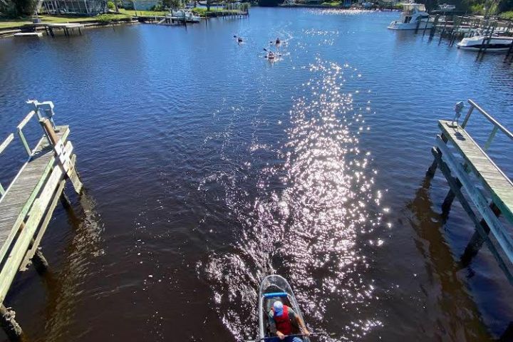 a boat floating along a river next to a body of water