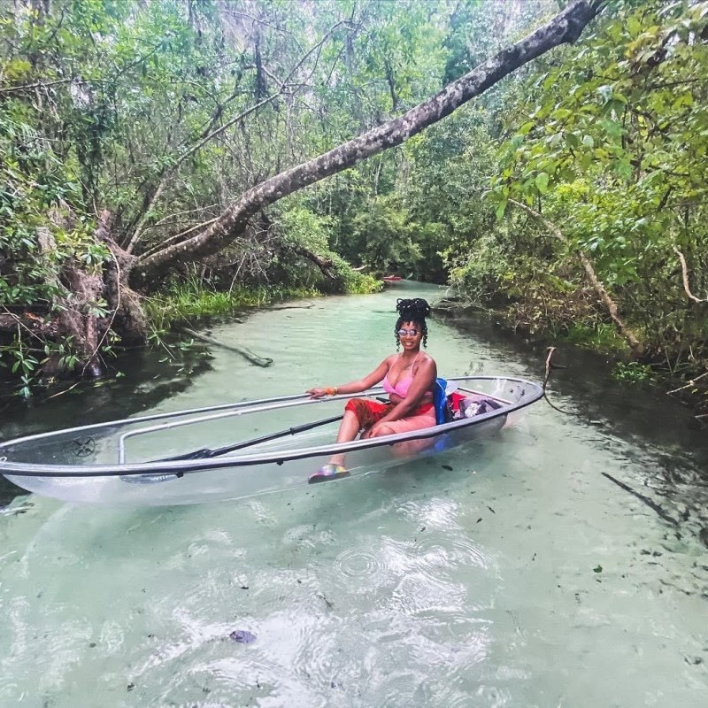 a person riding on the back of a boat next to a river
