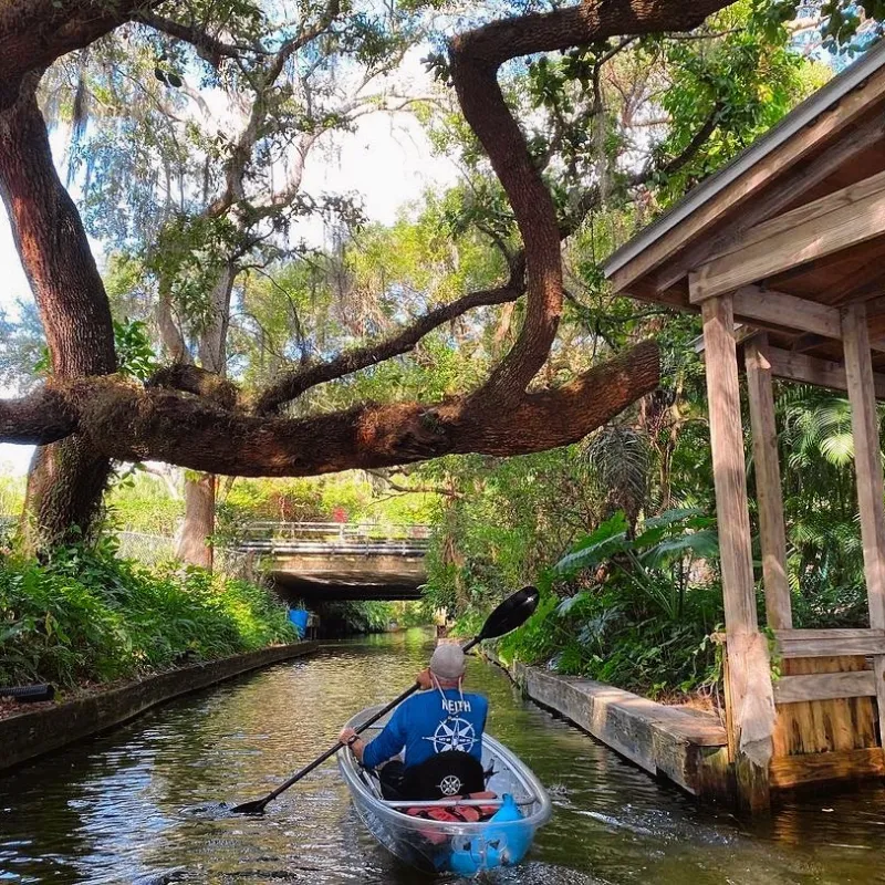 a man riding on the back of a boat next to a river