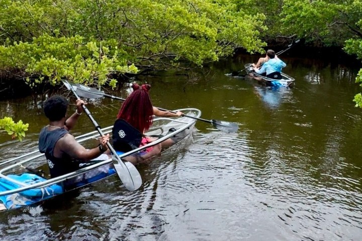 a man riding on the back of a boat next to a river