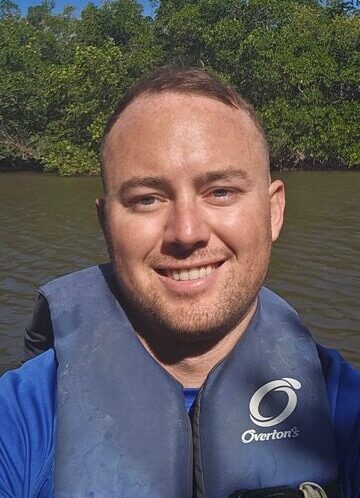 a man smiling with water in the background