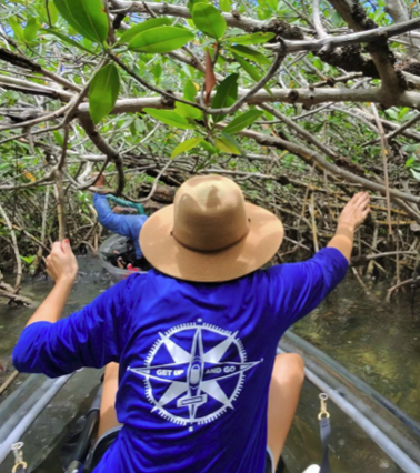 a person in a blue shirt standing in front of a tree