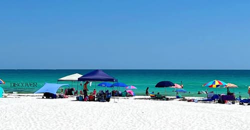 a group of lawn chairs sitting on top of a sandy beach