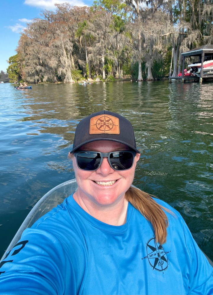 a man wearing sunglasses and sitting in a boat on a body of water