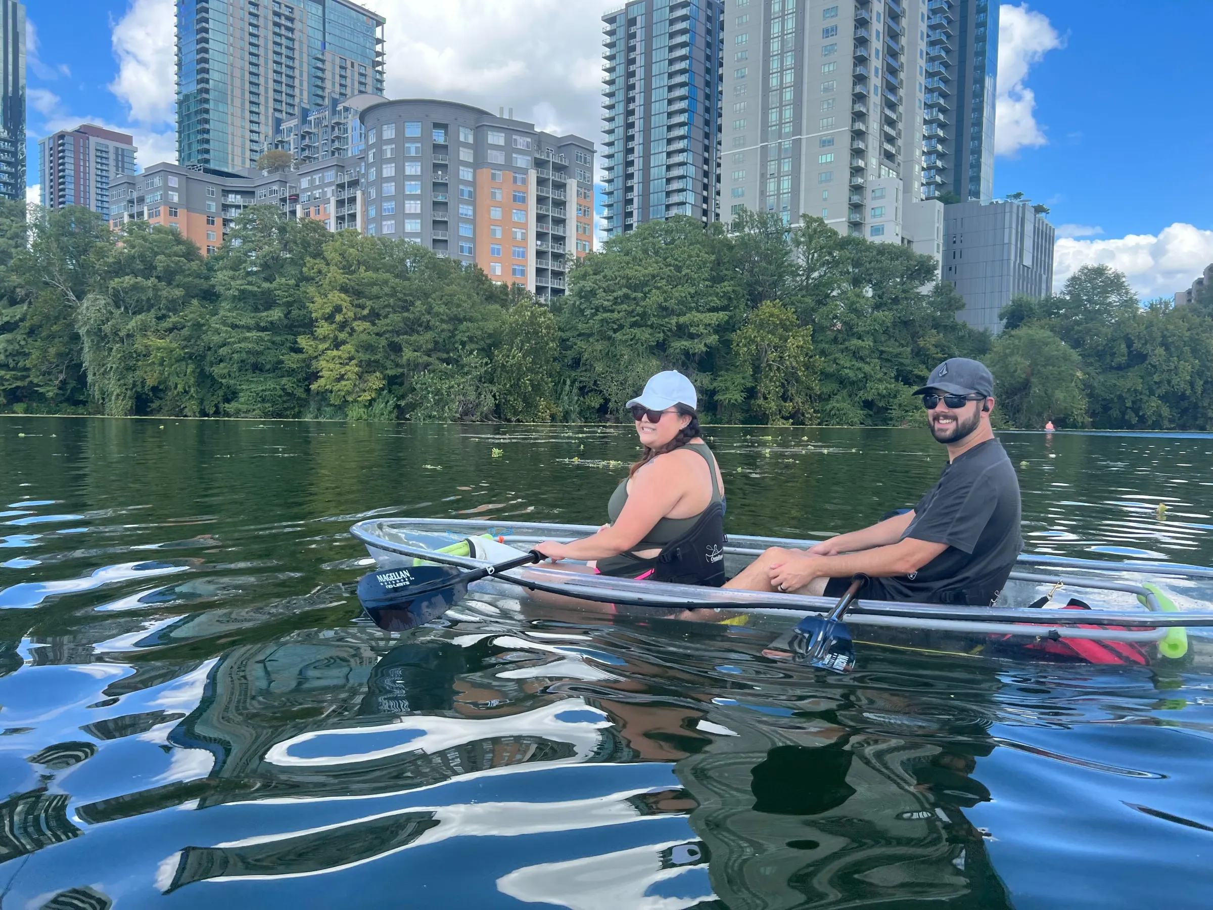 a man and woman riding on the back of a boat in the water