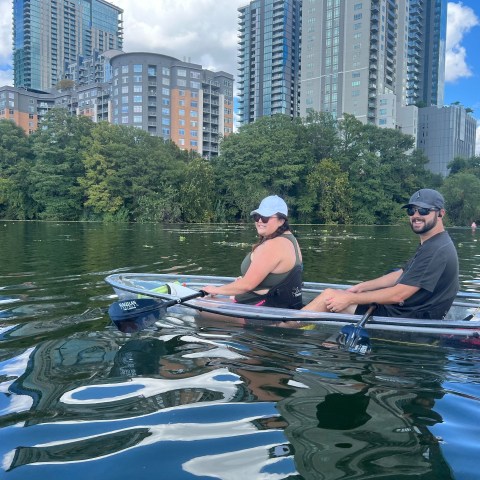 a man and woman riding on the back of a boat in the water