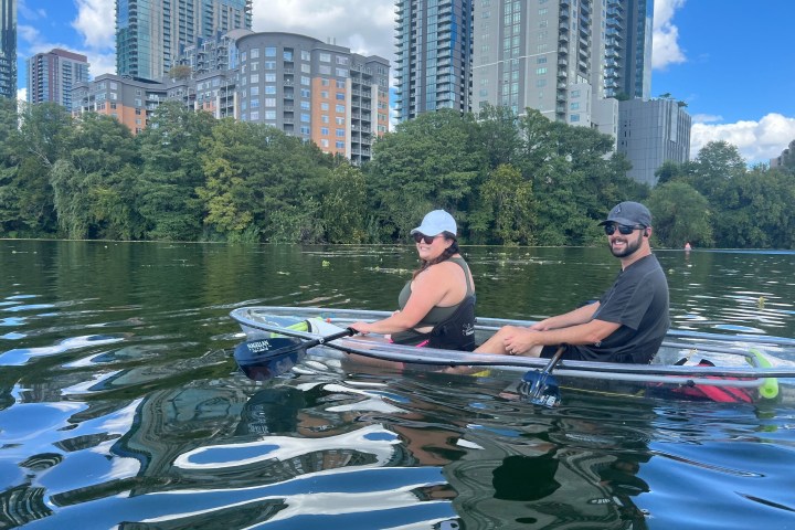 a man and woman riding on the back of a boat in the water