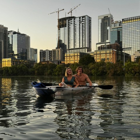a man floating in the water with a city in the background