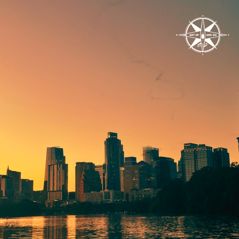 a bird flying over a city at sunset