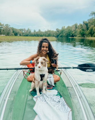 a woman sitting on a boat with a dog in a body of water