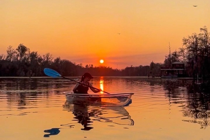 a small boat in a body of water with a sunset in the background