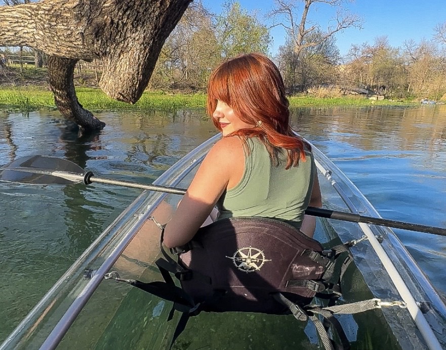a woman sitting next to a body of water