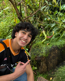 a young man sitting next to a tree