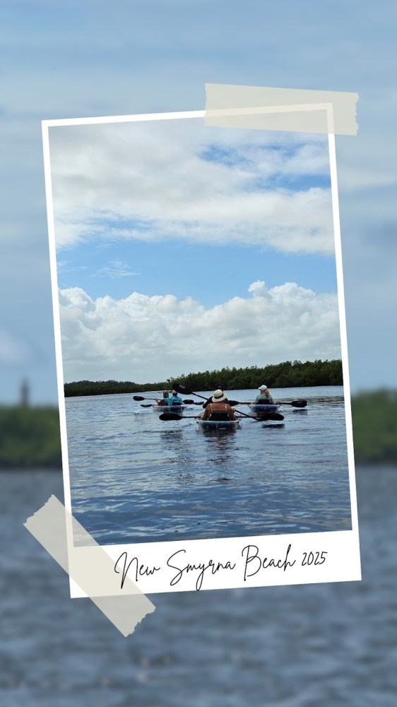 Three people kayaking on calm waters under a partly cloudy sky.