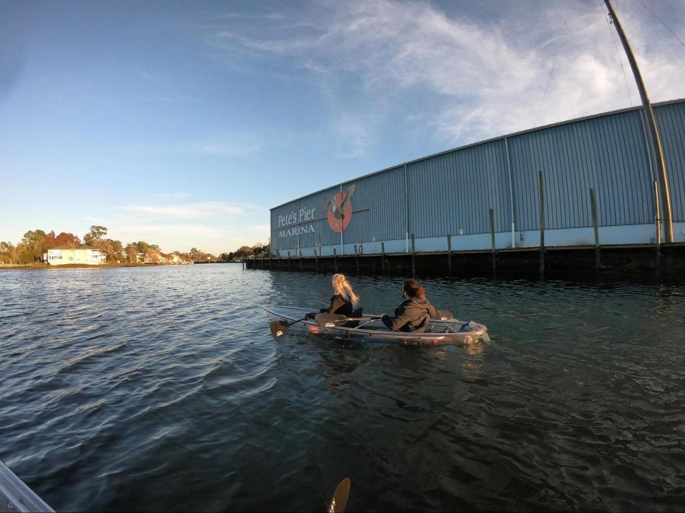 Two people kayaking near a marina with a large building labeled 'Pete's Pier Marina'.