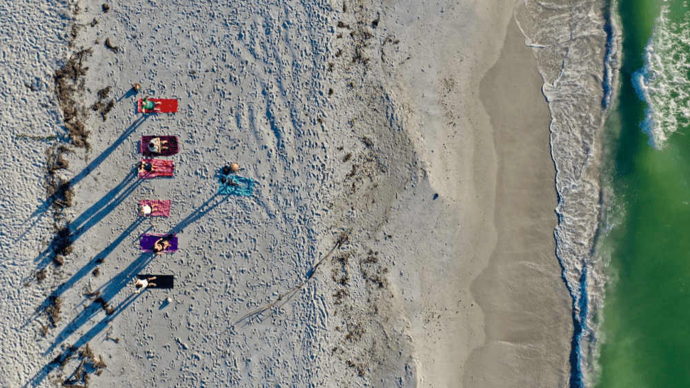 Aerial view of people sunbathing on beach with waves nearby.