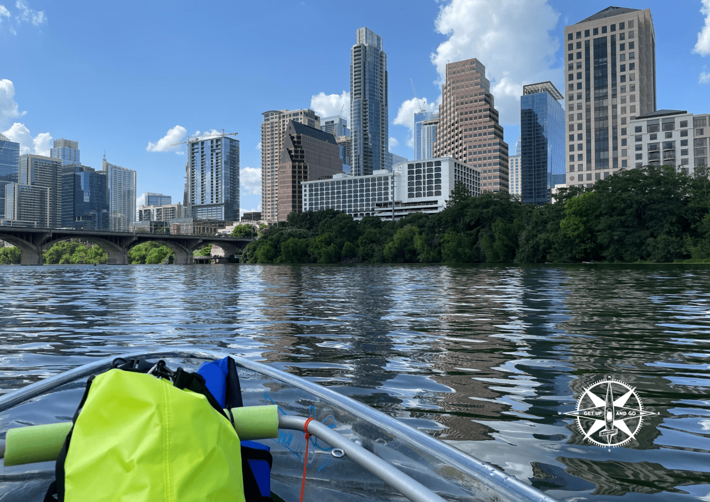 View of city skyline from kayak on river with clear skies.