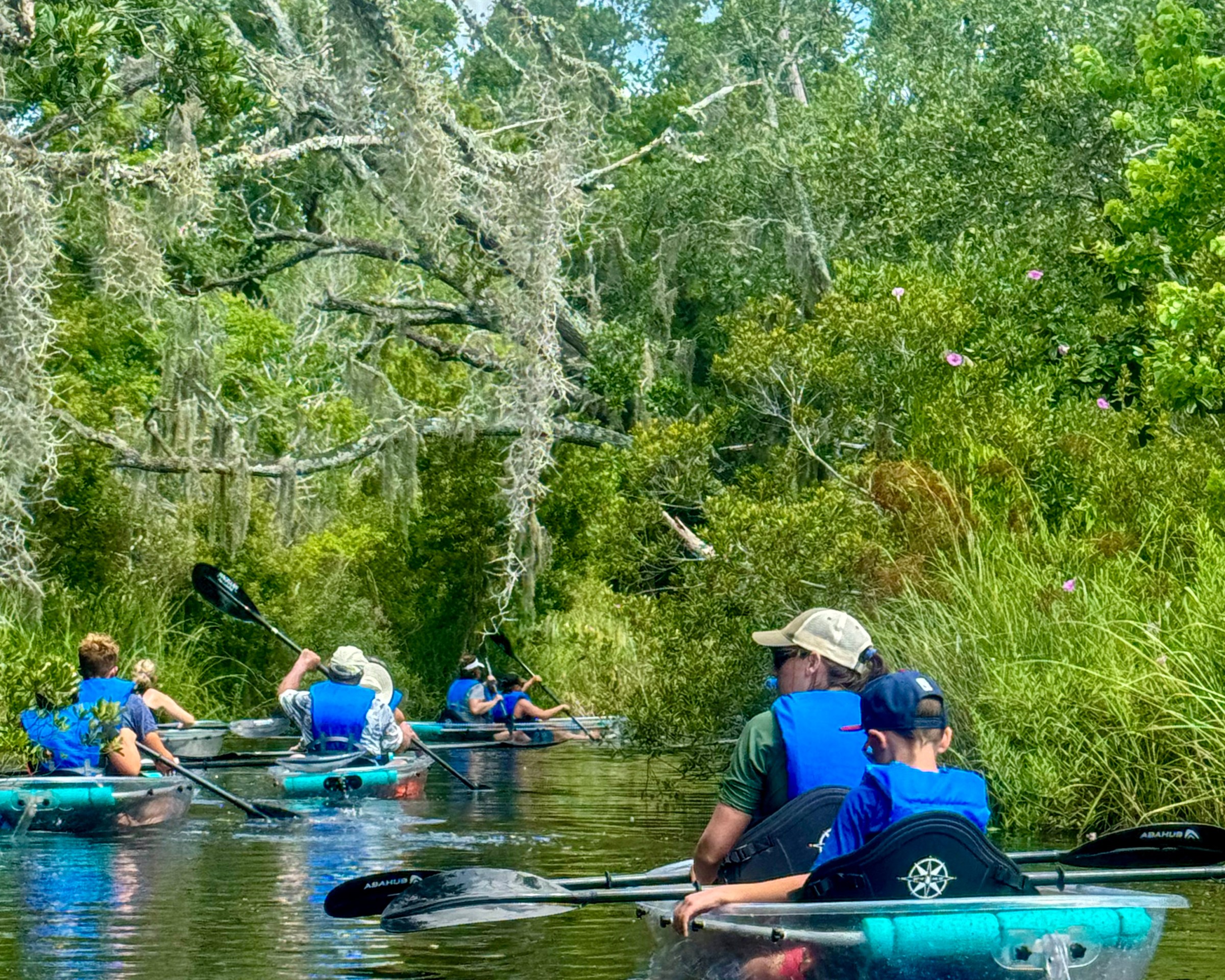 Group kayaking on a narrow waterway surrounded by lush greenery.