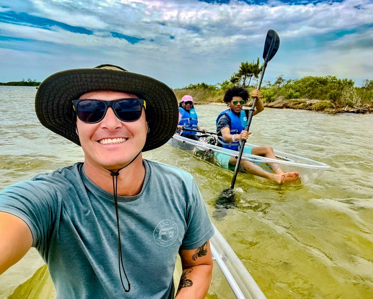 Group kayaking in clear water under a partly cloudy sky.