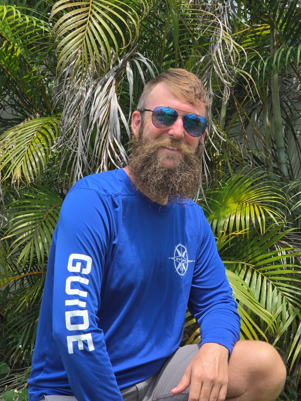 Person with wide-brim hat and sunglasses holding a paddle under clear blue sky.