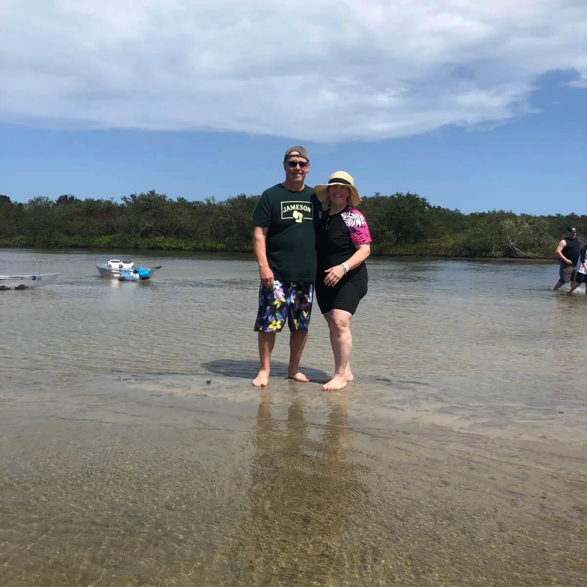 Two people standing in shallow water with a kayak in the background.