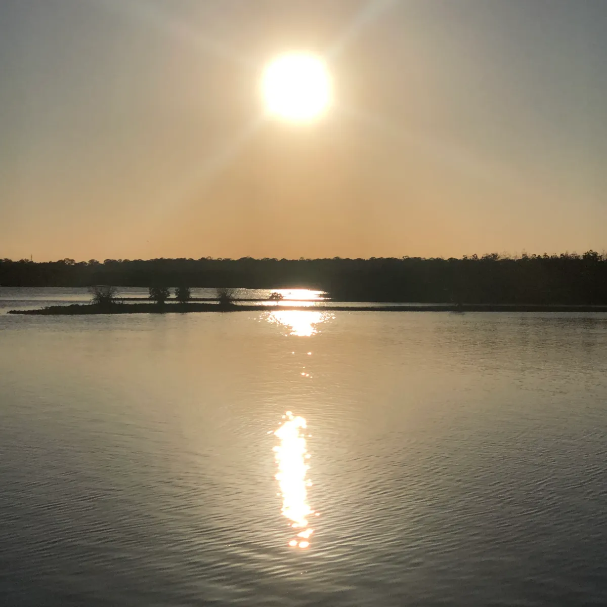 Sunset over a calm lake with reflection on water.