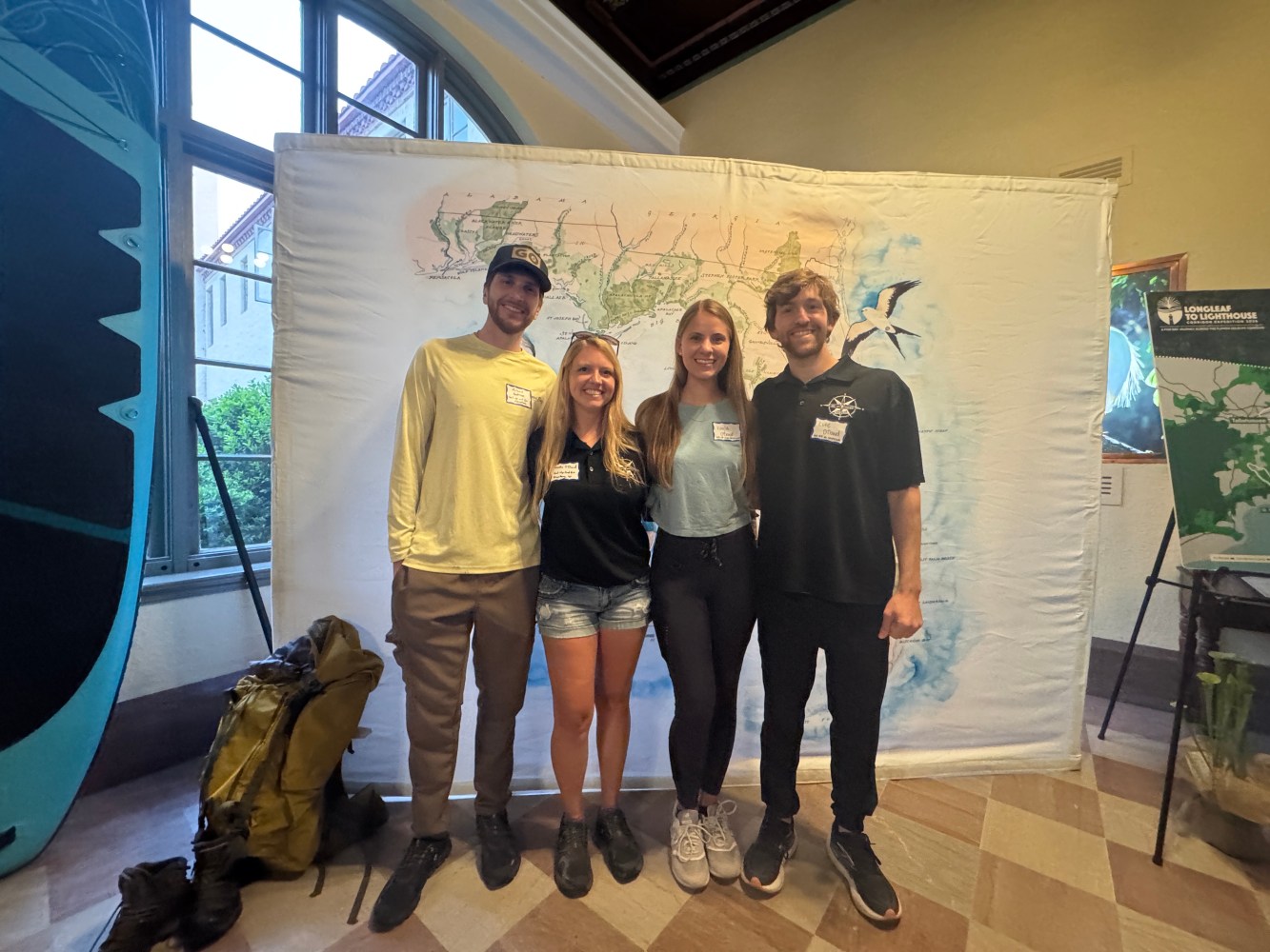 Four people standing in front of a large map display indoors.