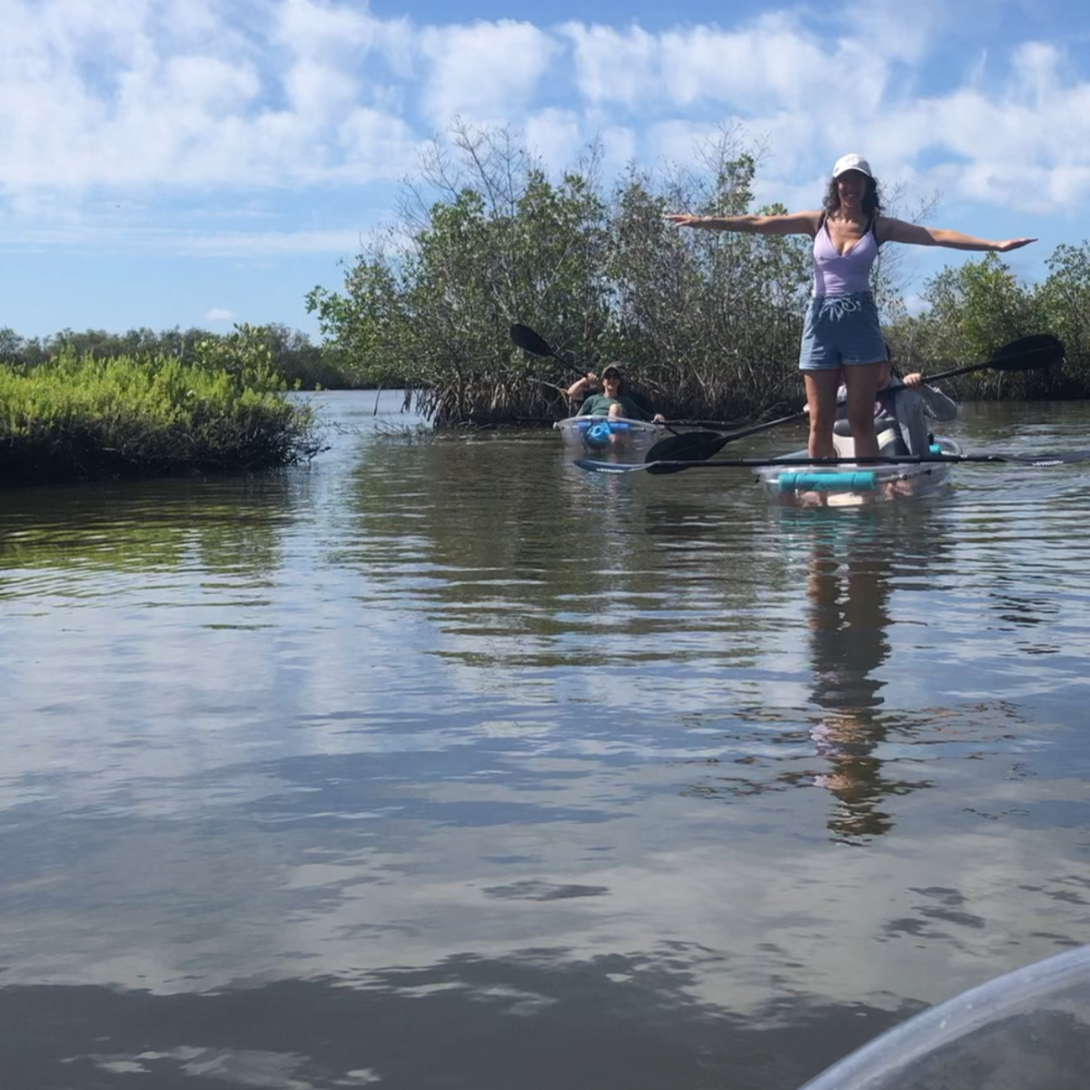Person standing on a paddleboard with arms outstretched on a calm lake.