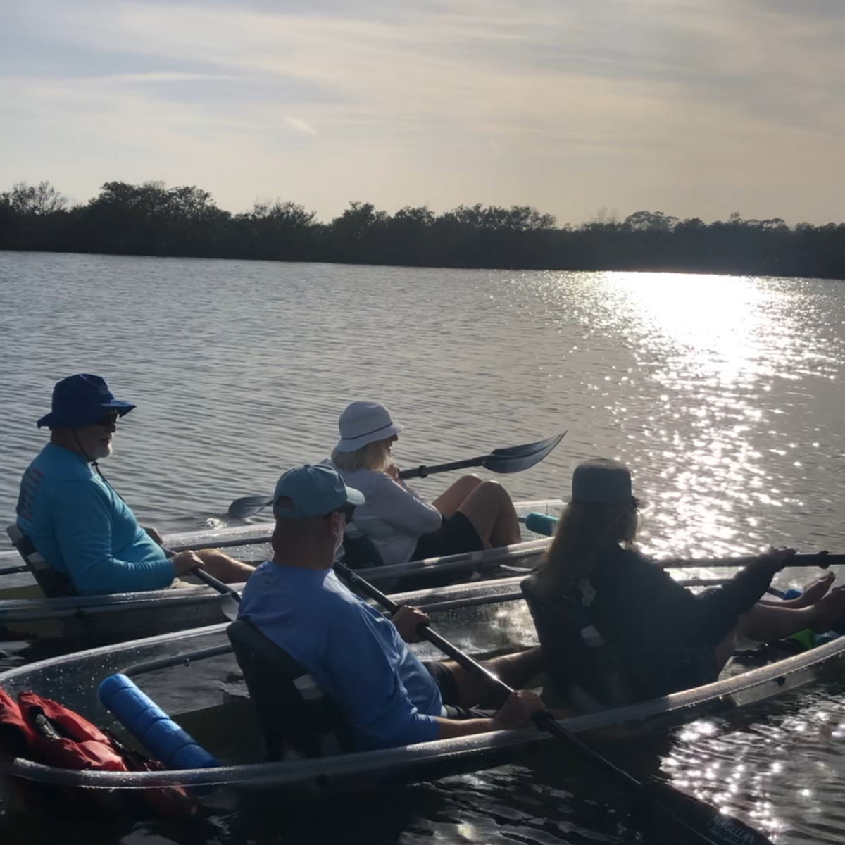 Four people in a boat rowing on a sunny lake.