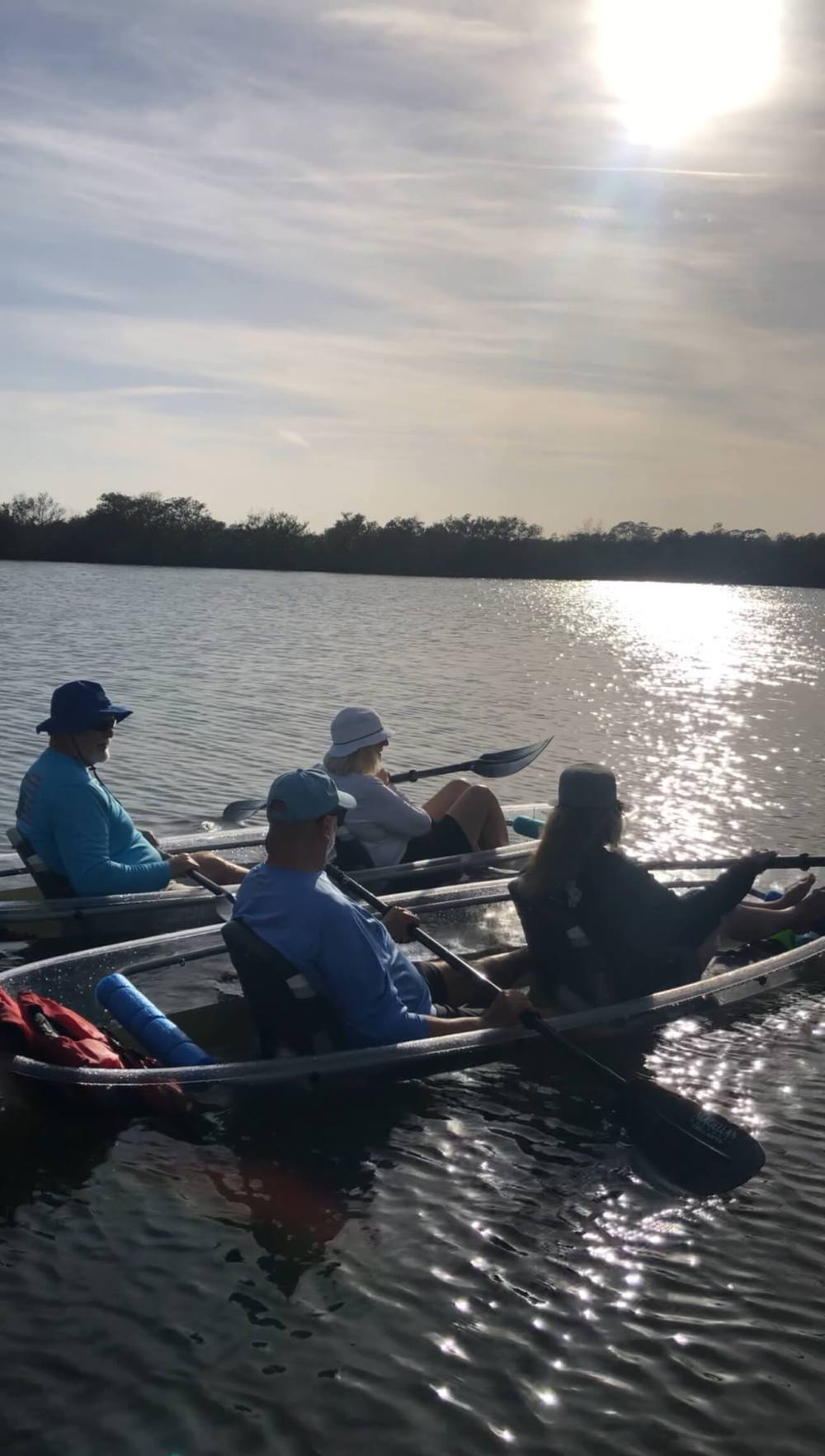 Four people kayaking on a sunny lake.