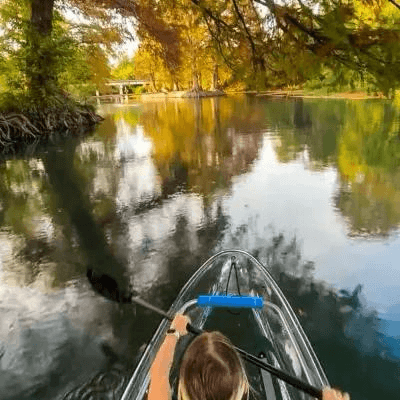 Person kayaking on a calm river surrounded by autumn trees.