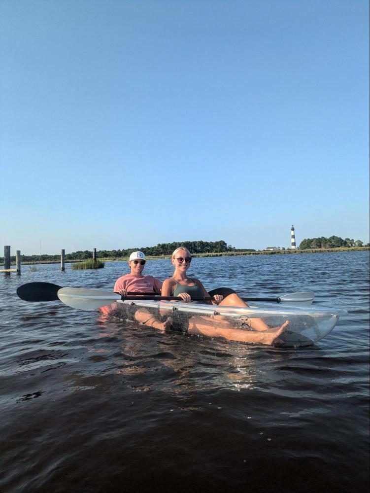 Two people kayaking in a transparent boat on a sunny day.