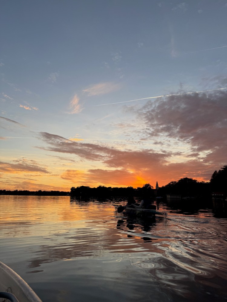 Silhouetted canoe on a lake at sunset with vibrant sky reflection.