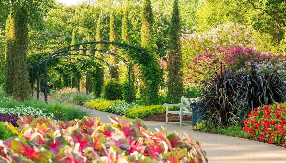 Colorful garden with flowers, a bench, pathway, and a metal archway.