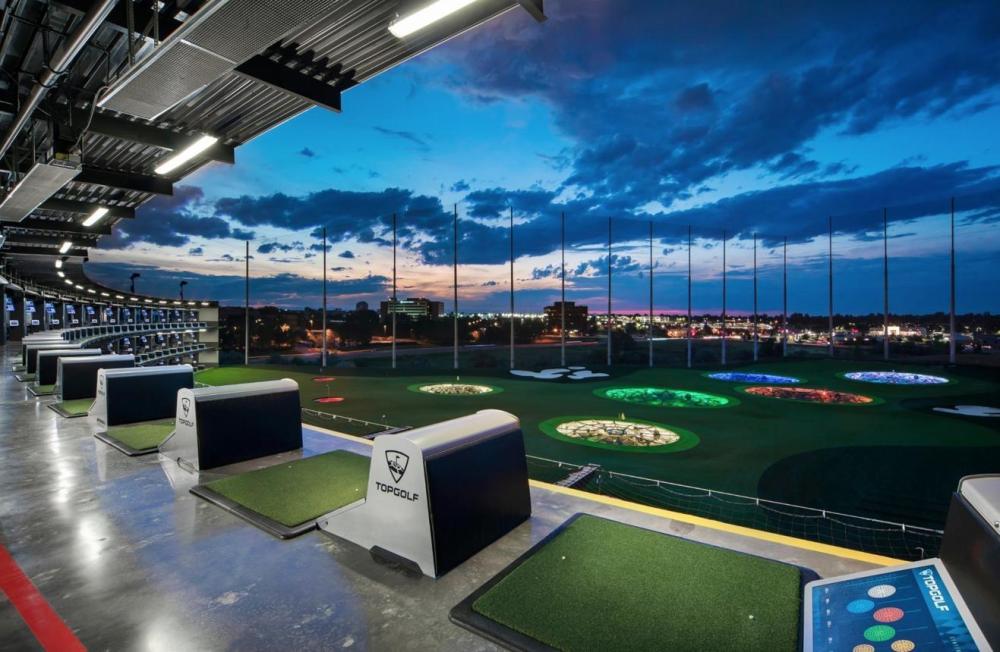Modern driving range with lit targets, sunset sky.