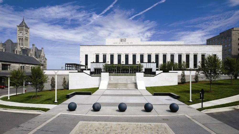 Exterior of a neoclassical building with a central staircase and large black spheres.